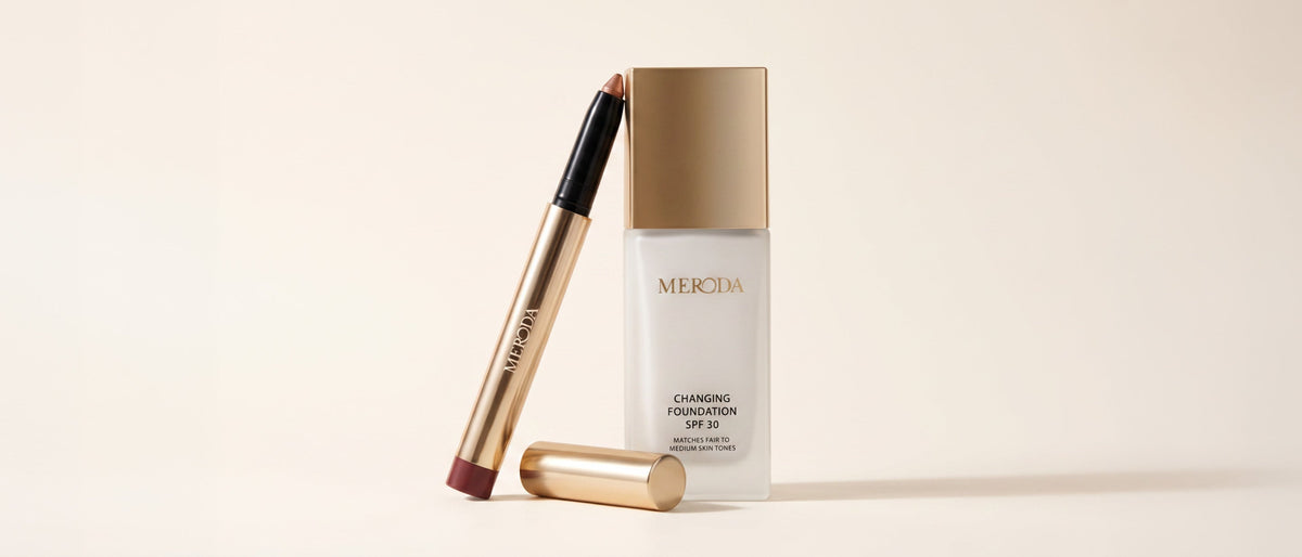 Meroda Changing Foundation bottle with a gold cap next to a golden cosmetic pen and cap.