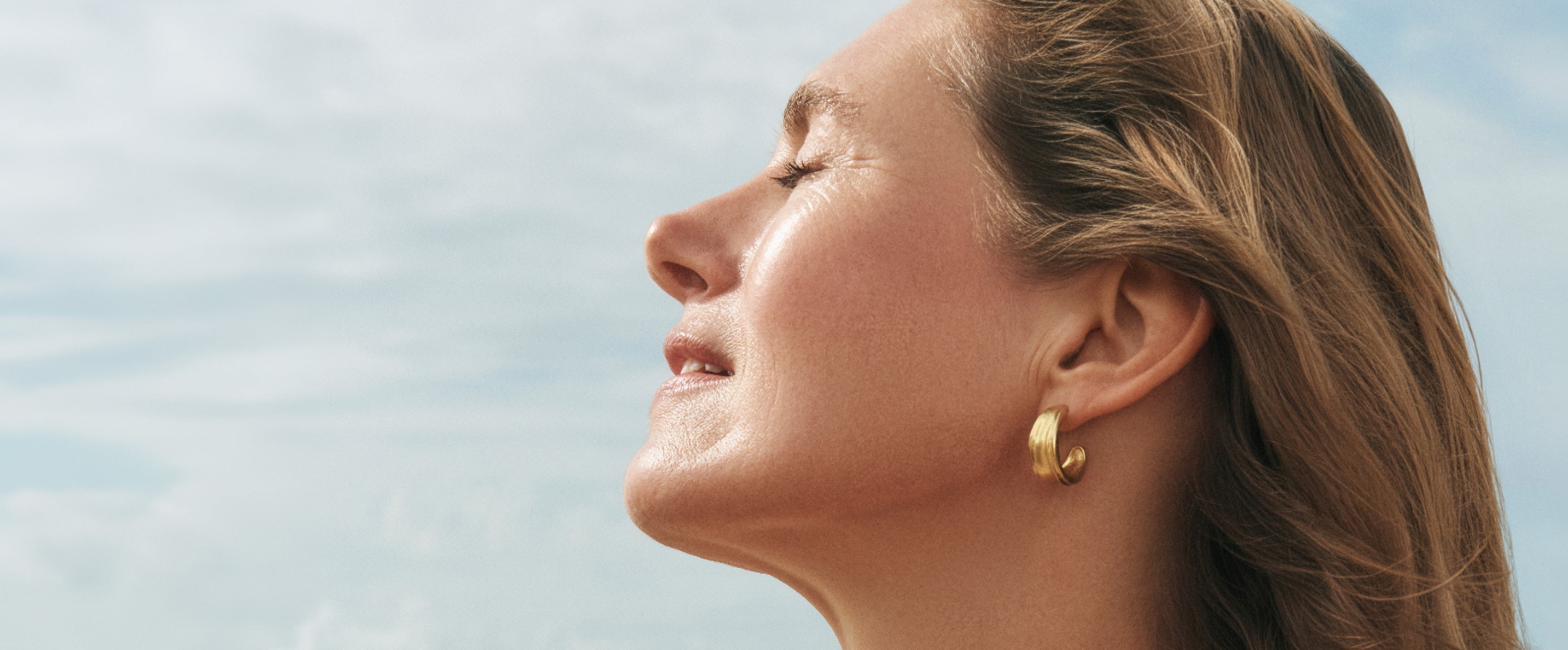 Woman with closed eyes against a clear blue sky