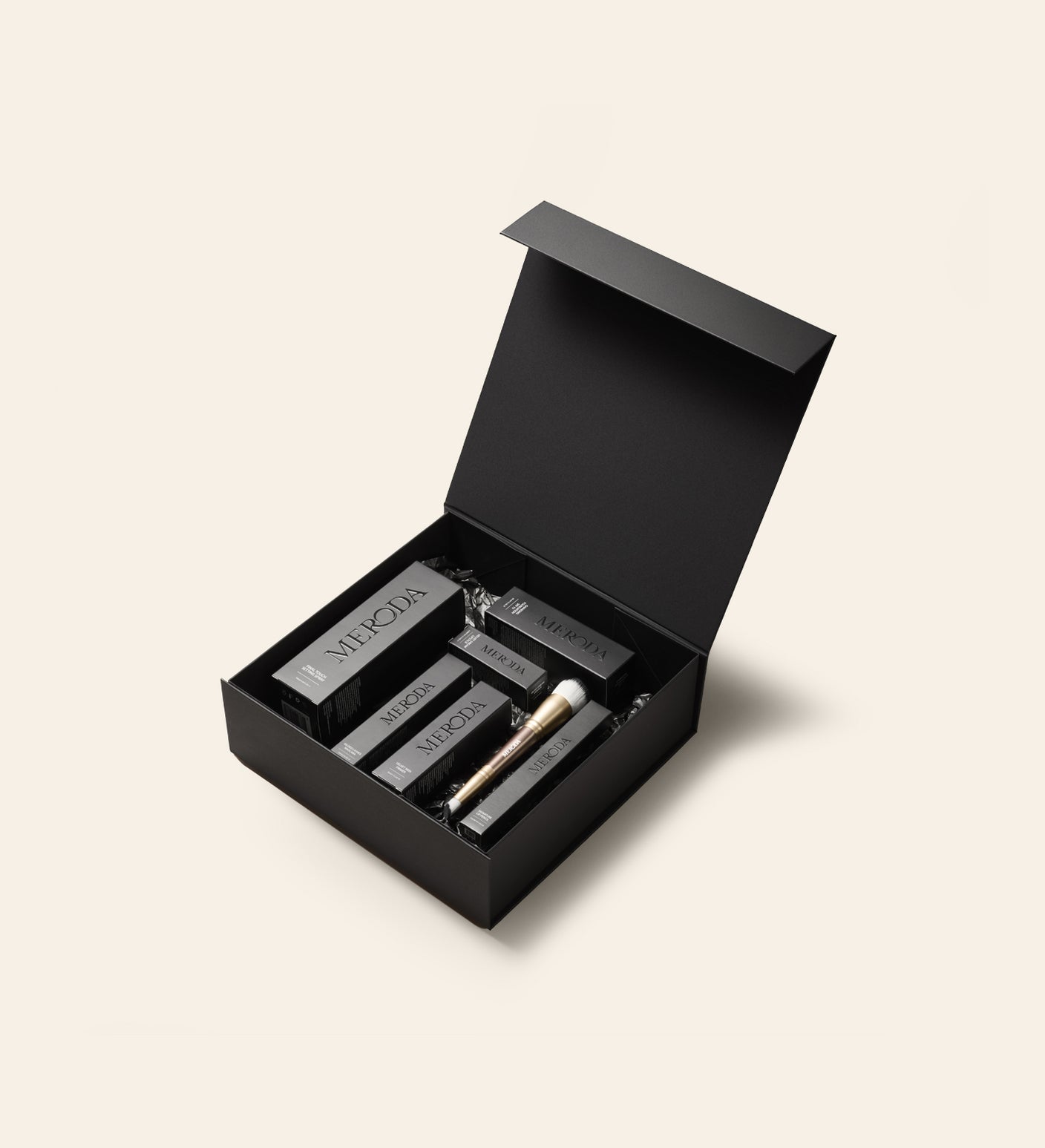 Gift Box noir mat à fermeture magnétique contenant des produits Meroda Cosmetics et un pinceau de maquillage doré.