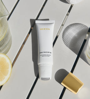 Daily Face SPF 40 tube with its cooling metal rollerball applicator on a bright table with a fresh lemon slice.