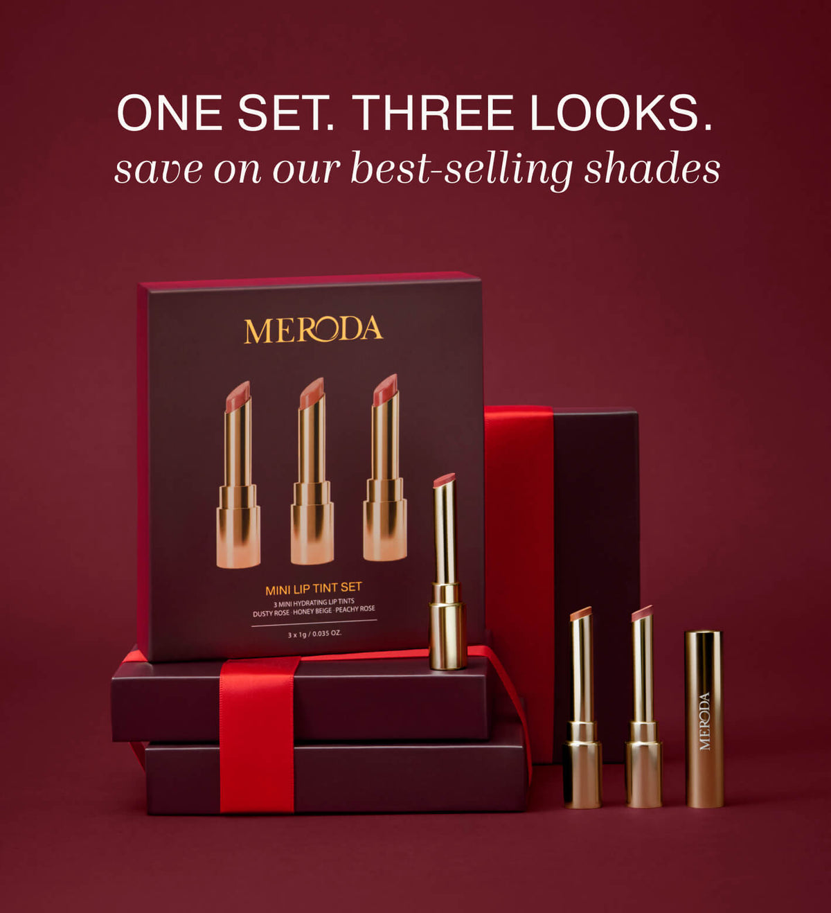 Mini Lip Tint Trio con tres tintes labiales hidratantes en envases dorados junto a una caja de regalo con cinta roja.