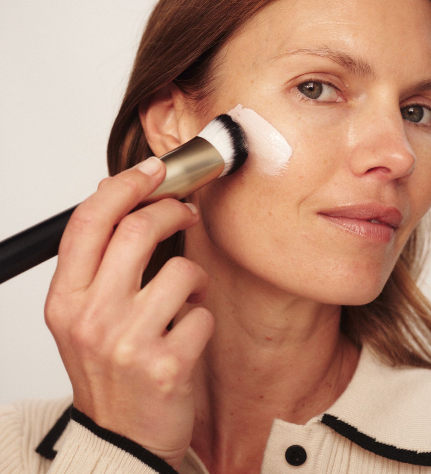 Model applying The Changing Foundation with a makeup brush for a natural, radiant finish