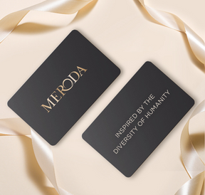 Meroda E-Gift Card : cartes noires aux inscriptions dorées et ruban de satin sur fond clair élégant.
